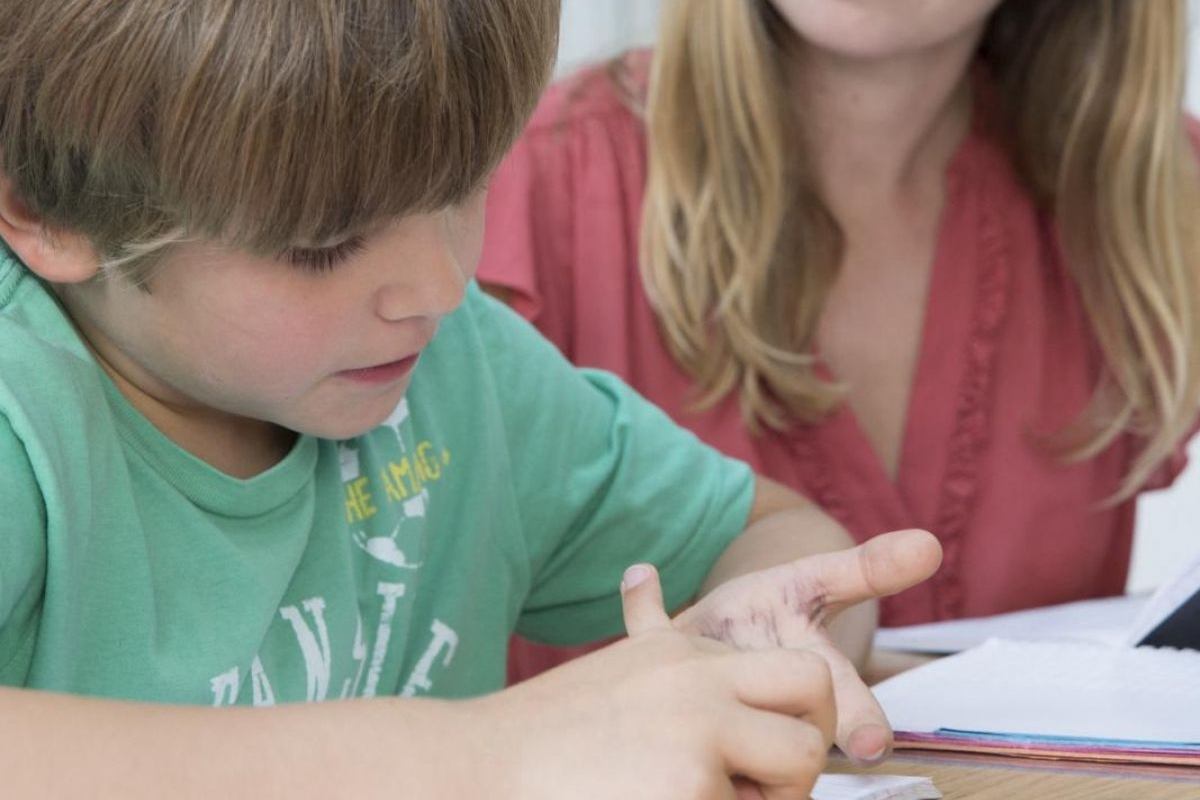 Enfant qui compte sur ses doigts avec une adulte à ses côtés, contexte d'évaluation cognitive