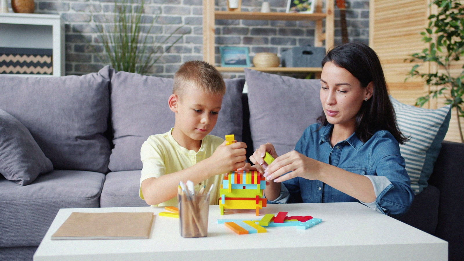 Psychologue et enfant construisant ensemble une tour de blocs colorés
